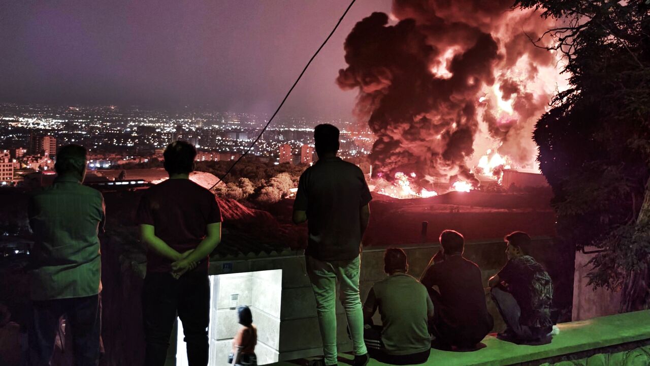 TEHRAN, IRAN - JUNE 15: People observe fire and smoke from an Israeli attack on the Shahran oil depot on June 15, 2025 in Tehran, Iran. Iran's foreign minister said the country would respond "decisively and proportionally" to a wave of attacks that Israel launched beginning in the early hours of June 13. The attacks targeted multiple military, scientific and residential locations, as well as senior government officials. (Photo by Stringer/Getty Images)