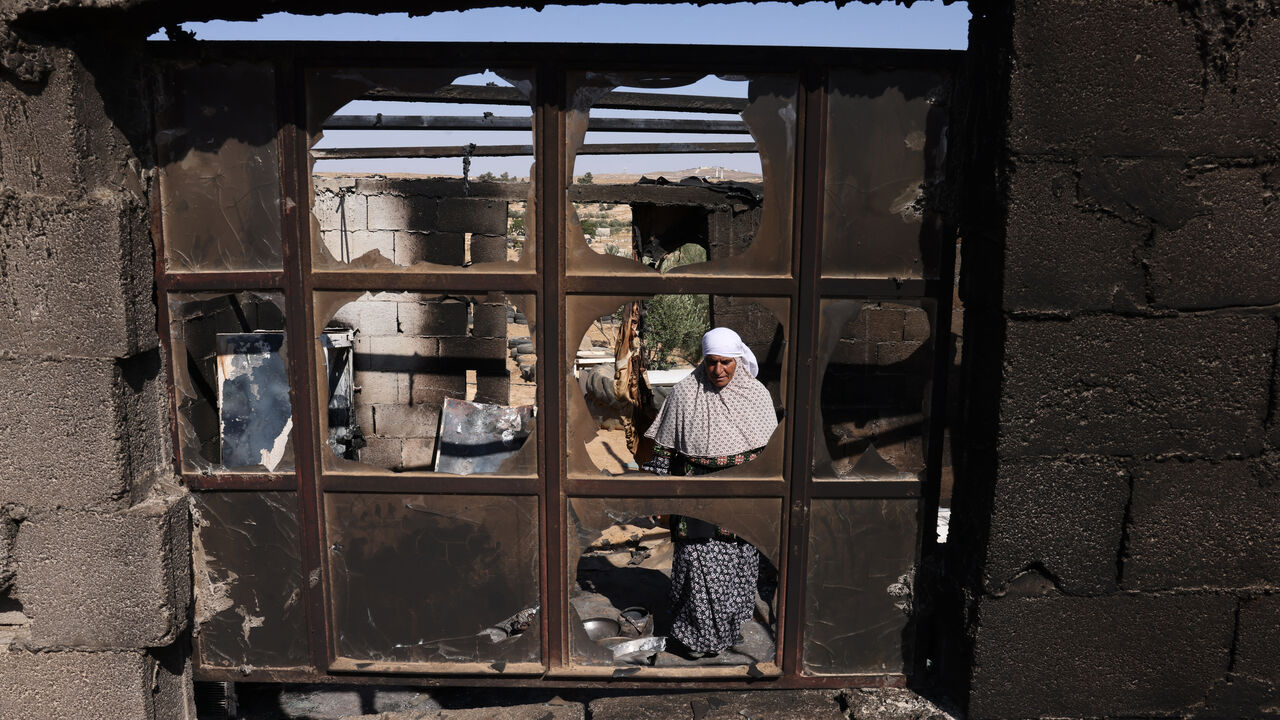 Palestinian Fawzya Ishreiteh clears burnt belongings in the living and kitchen area of her family house after a reported attack overnight by Israelis from a nearby settlement, in Susya south of Hebron city in the occupied West Bank on June 25, 2025. Israel has occupied the West Bank since 1967, and violence there has soared since the start of the Gaza war in 2023. The West Bank is home to about three million Palestinians, but also some 500,000 Israelis living in settlements that are illegal under internatio