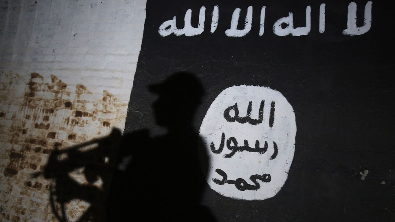 A member of the Iraqi forces walks past a mural bearing the logo of the Islamic State group in a tunnel that was reportedly used as a training center by the jihadists, on March 1, 2017, in the village of Albu Sayf, on the southern outskirts of Mosul.