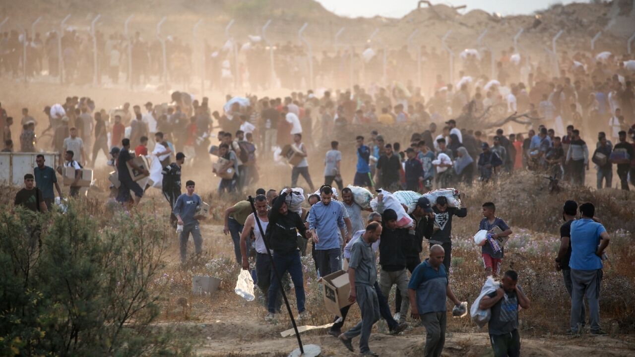 Palestinians carry supplies from a Gaza Humanitarian Foundation aid point in the central Gaza Strip