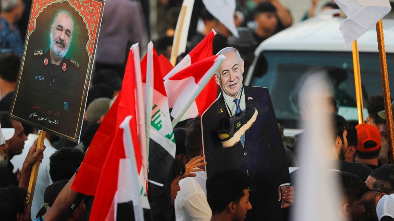 An Iraqi holds a picture of Major General Hossein Salami, head of the Iranian Revolutionary Guard, who was killed in an Israeli airstrike in Tehran, with another holding a cutout of Israeli Prime Minister Benjamin Netanyahu with a shoe around the neck during a protest in Baghdad An Iraqi holds a picture of Major General Hossein Salami, head of the Iranian Revolutionary Guard, who was killed in an Israeli airstrike in Tehran, with another holding a cutout of Israeli Prime Minister Benjamin Netanyahu with a shoe around the neck during a protest in Baghdad