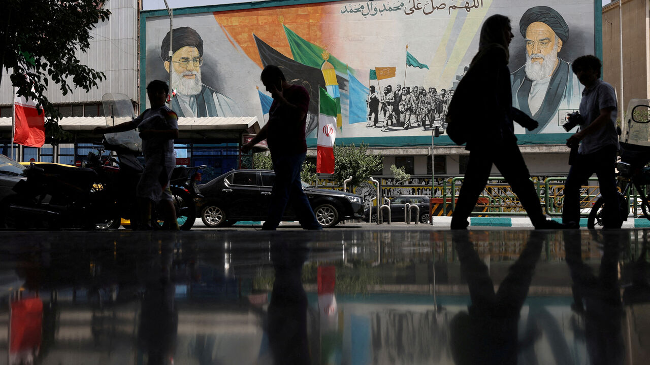 FILE PHOTO: People walk next to a mural with a picture of Iran's Supreme Leader, Ayatollah Ali Khamenei, on a street, early hours of ceasefire, in Tehran, Iran, June 24, 2025. Majid Asgaripour/WANA (West Asia News Agency) via REUTERS/File Photo