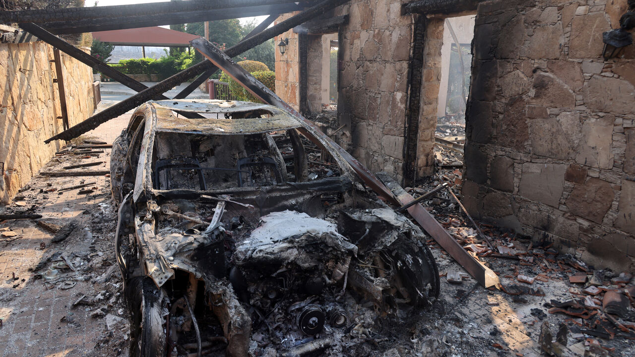 A burnt car is seen, as a wildfire burns in the village of Souni, near Limassol, Cyprus July 24, 2025. REUTERS/Yiannis Kourtoglou