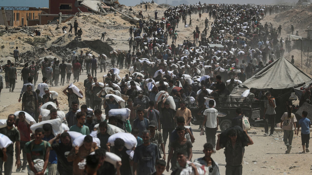 FILE PHOTO: Palestinians carry aid supplies that entered Gaza through Israel, in Beit Lahia, northern Gaza Strip, July 27, 2025. REUTERS/Mahmoud Issa/File Photo