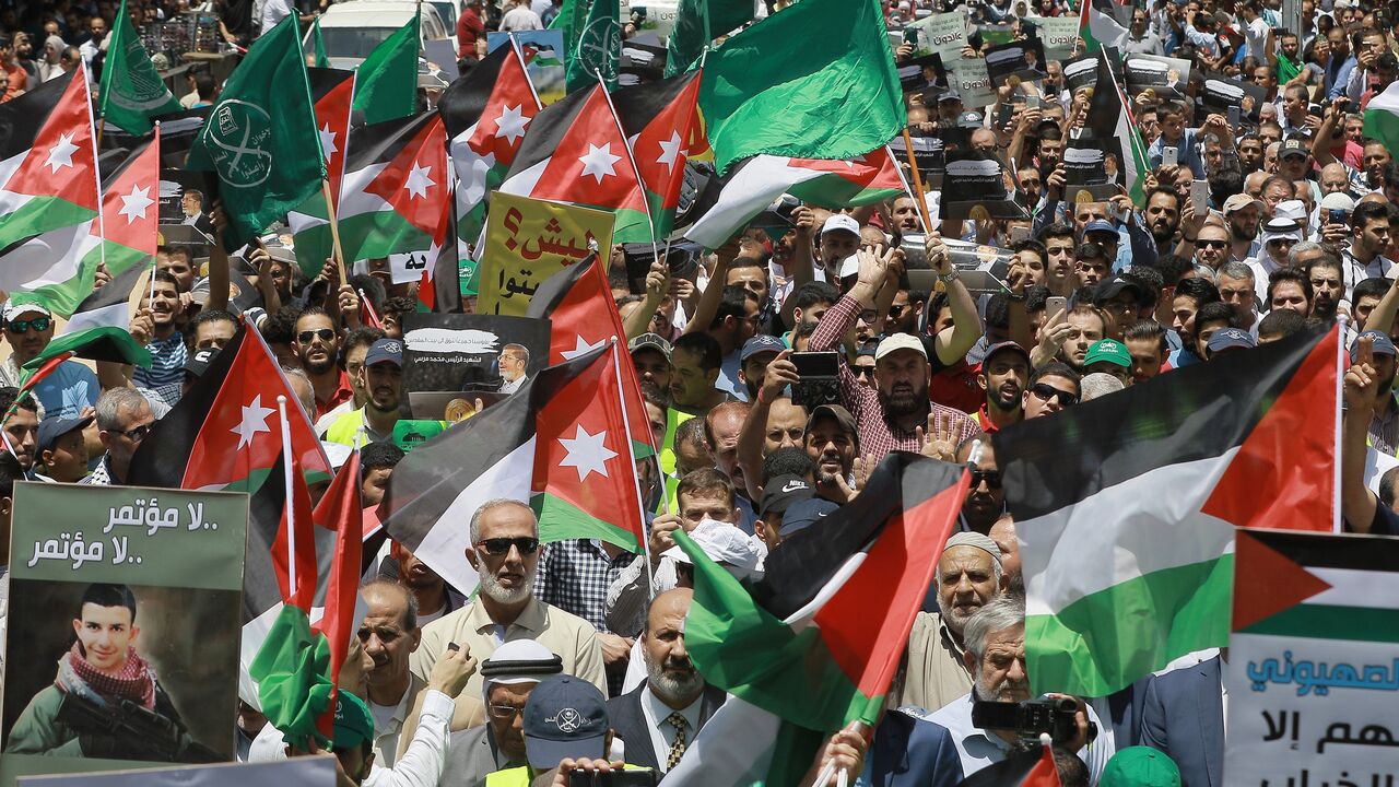 Flags of Jordan and the Muslim Brotherhood are waved with other protest signs denouncing the US-led Middle East economic conference in Bahrain, in the Jordanian capital, Amman, on June 21, 2019.