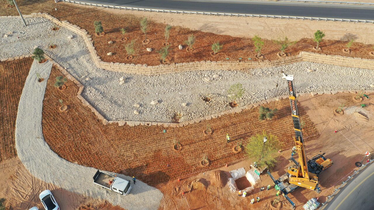 An aerial picture shows workers using a crane to plant trees in a park project by the roadside in the Saudi capital Riyadh, on March 29, 2021. - Although the OPEC kingpin seems an unlikely champion of clean energy, the "Saudi Green Initiative" aims to reduce emissions by generating half of its energy from renewables by 2030. (Photo by - / AFP) (Photo by -/AFP via Getty Images)