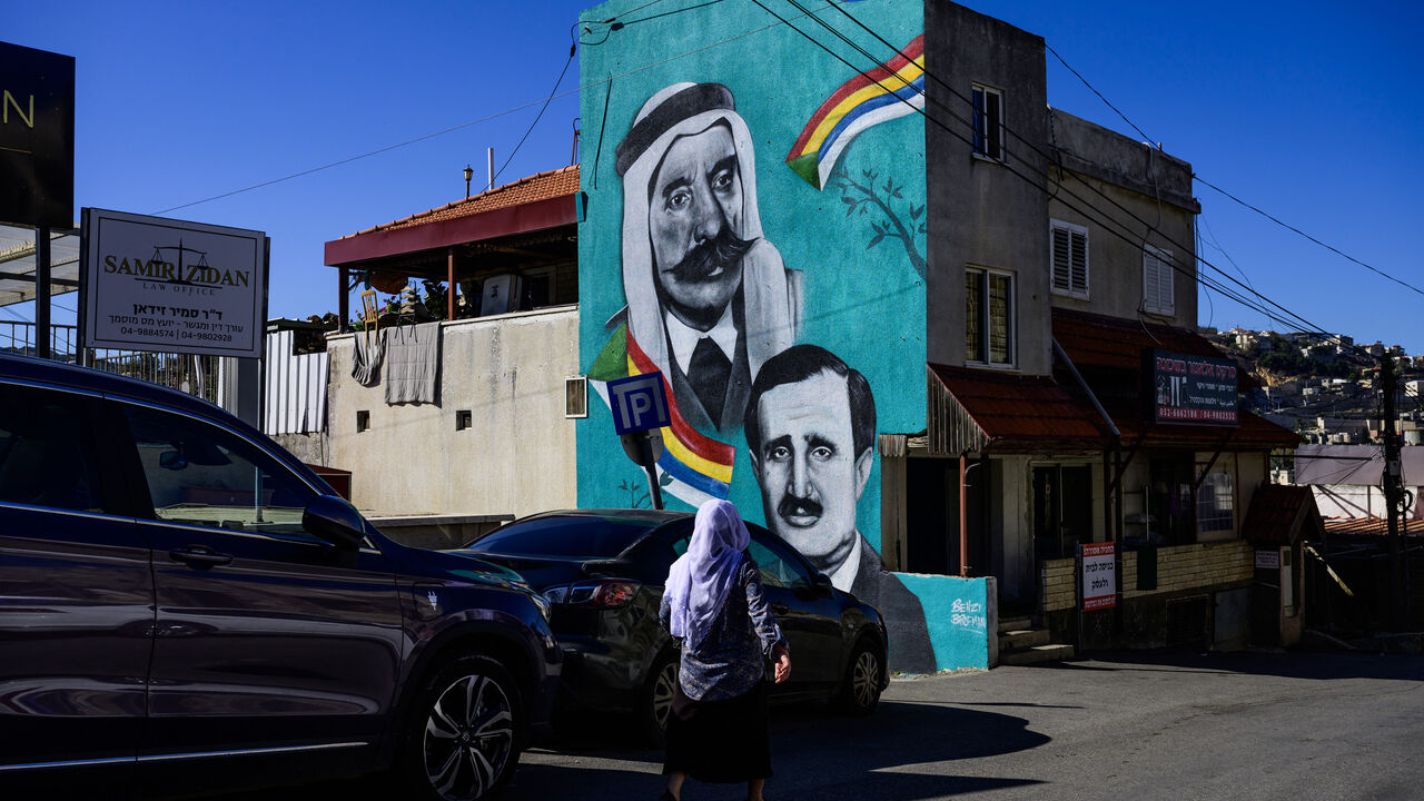 A woman walks past a mural depicting Lebanese Druze politician Walid Jumblatt (bottom, R) and Syrian Druze nationalist leader Sultan al-Atrash, in the predominantly Druze city of Beit Jann on November 16, 2023. Around 150,000 Druze, Arab adherents of an esoteric offshoot of Shiite Islam, live in Israel. Most identify as Israelis and the men -- not women -- are conscripted into the military, many serving in combat units. The Druze community is concentrated in 16 villages in northern Israel, among them Beit J