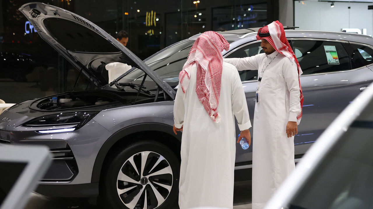 Men inspect an electric car at a showroom in Riyadh on June 8, 2024.
