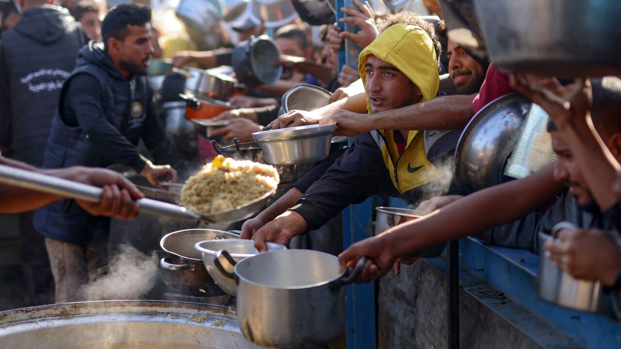Palestinians wait in a queue to receive food outside a distribution center south of Khan Younis, on Dec. 6, 2024, amid the ongoing war between Israel and Hamas.