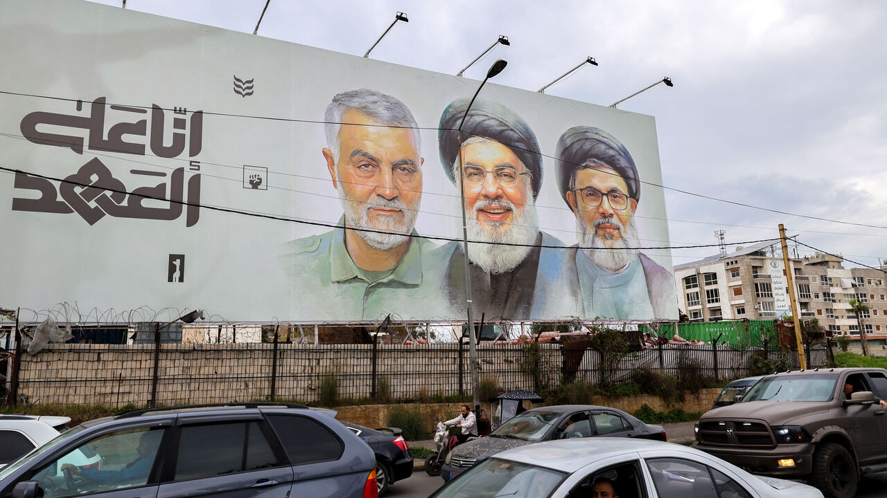 Traffic moves beneath a banner depicting the slain leader of the Lebanese Shiite Islamist movement Hezbollah Hassan Nasrallah (C) and his deputy Hashem Safieddine (C-R) as well as that of slain Iranian General Qassem Soleimani on Beirut Airport Road, in Beirut on February 19, 2025. The pro-Iran group has called for a huge turnout when Nasrallah, killed in a September Israeli strike, is laid to rest in the Lebanese capital on February 23. (Photo by ANWAR AMRO / AFP) (Photo by ANWAR AMRO/AFP via Getty Images)