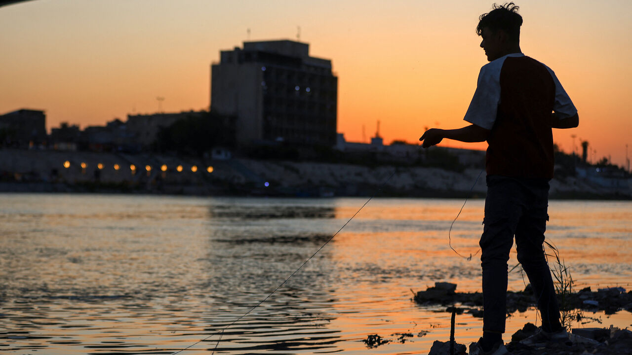 An Iraqi boy catches fish in the Tigris River in central Baghdad as the sun sets, on April 15, 2025.