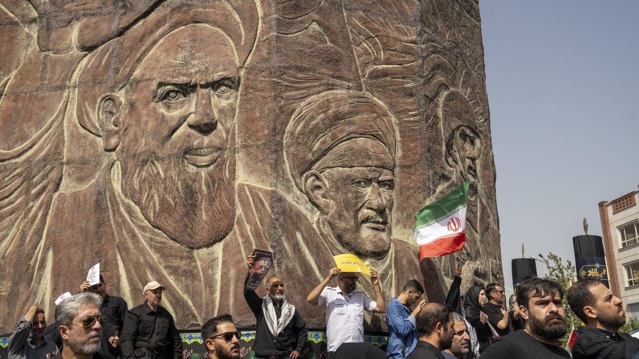 People stand near a monument to Iran's late former leader, Ayatollah Khomeini, as thousands of Iranians attend the funeral ceremony for approximately 60 people killed in Israeli strikes on Iran, on June 28, 2025, in Tehran, Iran. 