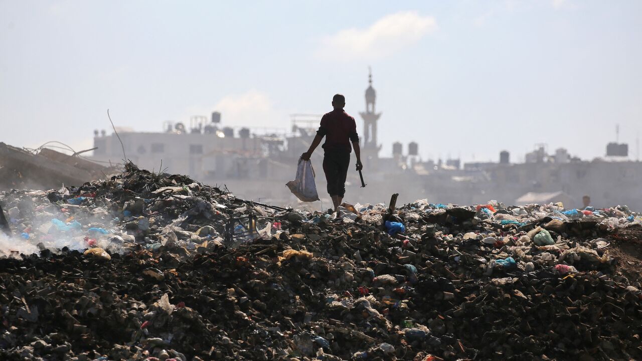 A Palestinian man searches for things to rescue at a garbage waste dump in the Al-Bureij camp in the central Gaza Strip on July 7, 2025.