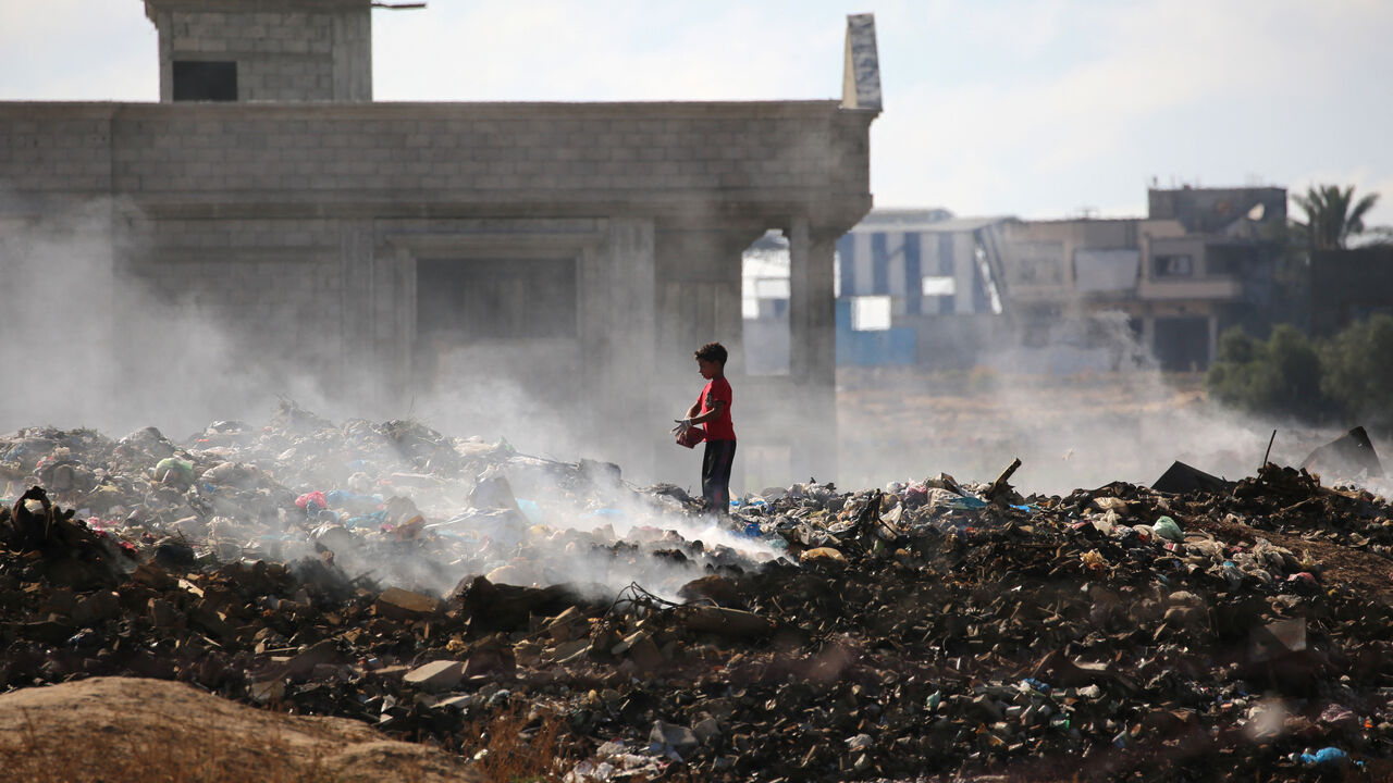 A Palestinian boy searches for things to rescue at a garbage waste dump in the Al-Bureij camp in the central Gaza Strip on July 7, 2025.
