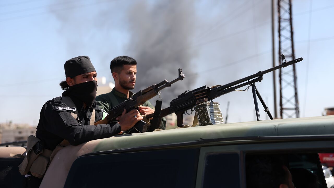 Syrian security forces stand with their guns atop a truck on July 15, 2025, near Suwayda, Syria.