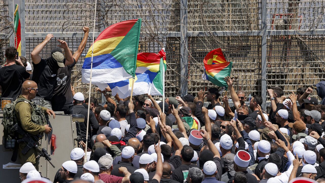 Members of the Druze community demonstrate before Israeli forces by the barbed-wire fence separating the Israeli-annexed Golan Heights and Syria near Majdal Shams, on July 16, 2025.