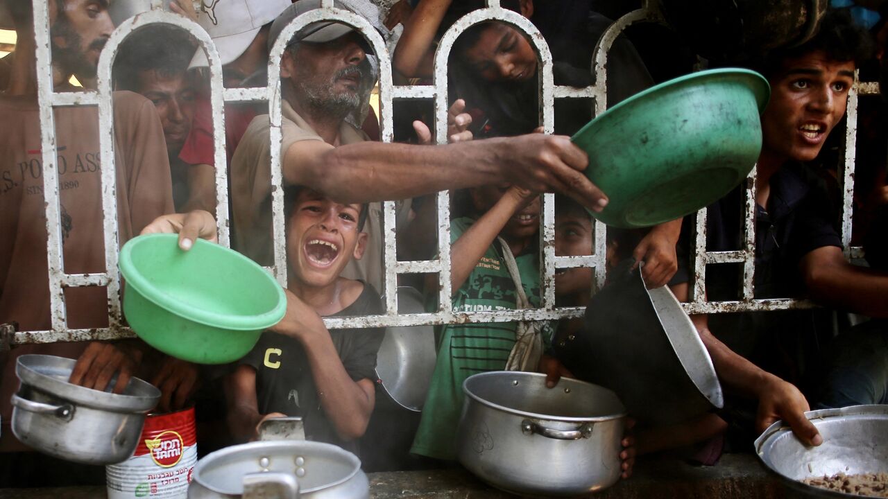Palestinians shove to receive a hot meal at a charity kitchen in the Mawasi area of Khan Yunis in the southern Gaza Strip on July 22, 2025.