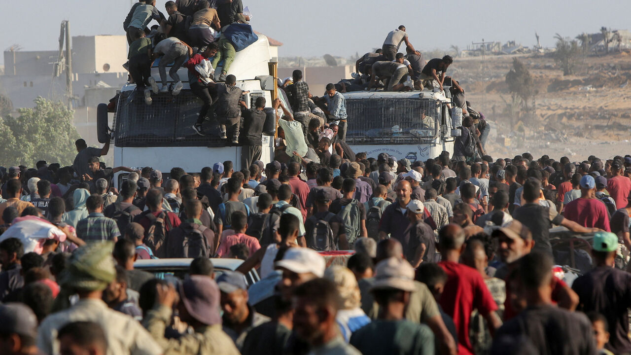 Palestinians climb onto trucks as they seek aid supplies in Khan Younis, southern Gaza Strip, August 4, 2025. REUTERS/Hatem Khaled