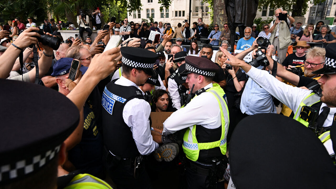 Police officers detain a demonstrator, as people hold placards that read "I oppose genocide, I support Palestine Action" during a rally organised by Defend Our Juries, challenging the British government's proscription of "Palestine Action" under anti-terrorism laws, in Parliament Square, in London, Britain, August 9, 2025. REUTERS/Jaimi Joy