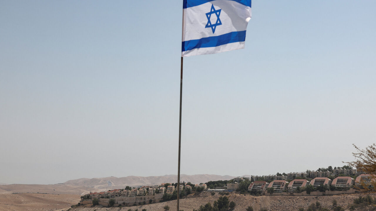 FILE PHOTO: An Israeli flag flutters, as part of the Israeli settlement of Maale Adumim is visible in the background, in the Israeli-occupied West Bank, August 14, 2025. REUTERS/Ronen Zvulun/File Photo