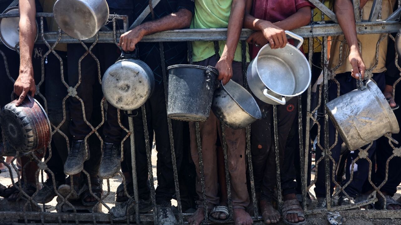 Palestinians carry empty pots as they wait to receive lentil soup at a food distribution point in Gaza City on August 2, 2025
Palestinians carry empty pots as they wait to receive lentil soup at a food distribution point in Gaza City on August 2, 2025