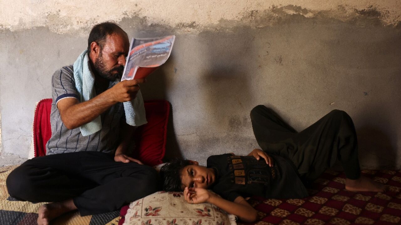 An Iraqi man fans his son at his home south of Hilla amid the heat of August An Iraqi man fans his son at his home south of Hilla amid the heat of August