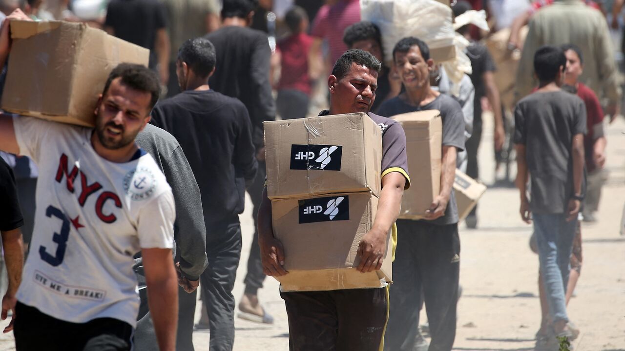 People carry boxes of relief supplies from the Gaza Humanitarian Foundation (GHF) as displaced Palestinians return from an aid distribution center in the central Gaza Strip on May 29, 2025.