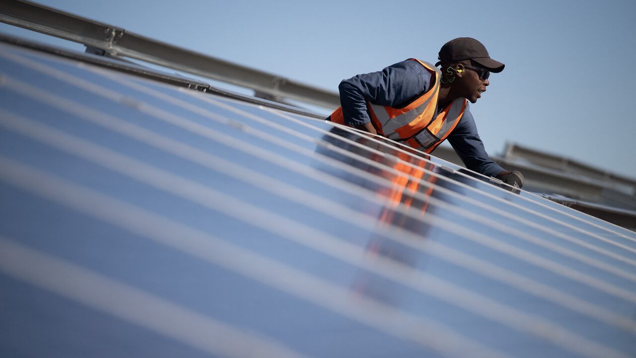 A worker fits solar panels onto frames during construction at South Africa's first municipally owned solar plant, during International World Environment Day, on June 5, 2025, in Atlantis near Cape Town.