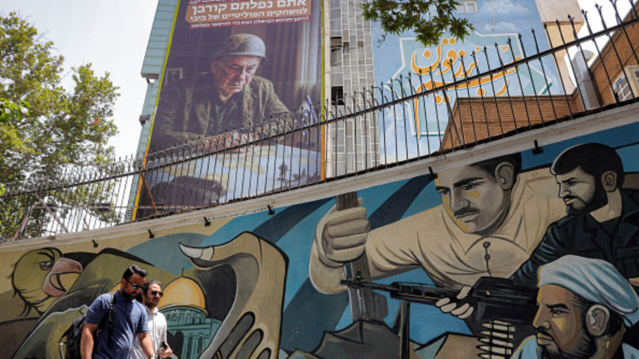 Pedestrians walk past a mural at Palestine Square in central Tehran on July 8, 2025, as an anti-Israeli billboard is displayed on the facade of a building depicting the Israeli prime minister Benjamin Netanyahu with text in Persian and Hebrew reading "Netanyahu lost another war; you fell victim to Bibi's political games; Where will the next failure to stay in power occur?" (Photo by -- / AFP) (Photo by --/AFP via Getty Images)