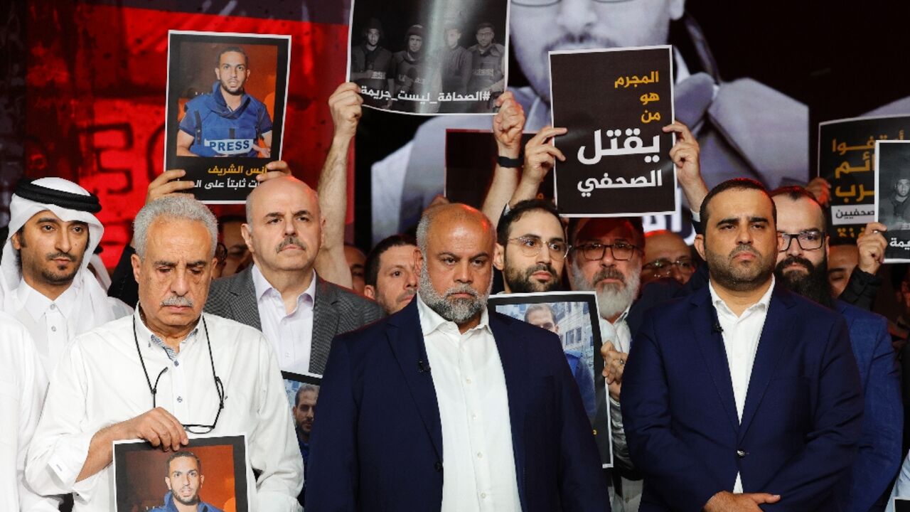 Wael Al-Dahdouh, Al Jazeera's Gaza bureau chief, stands with anchor and presenter Mohamed Krichen and presenter Tamer Almisshal during a moment of silence to honour five of their colleagues killed in an overnight Israeli strike in Gaza City