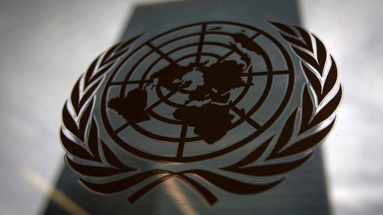 The United Nations headquarters building is pictured through a window with the UN logo in the foreground in the Manhattan borough of New York August 15, 2014. REUTERS/Carlo Allegri