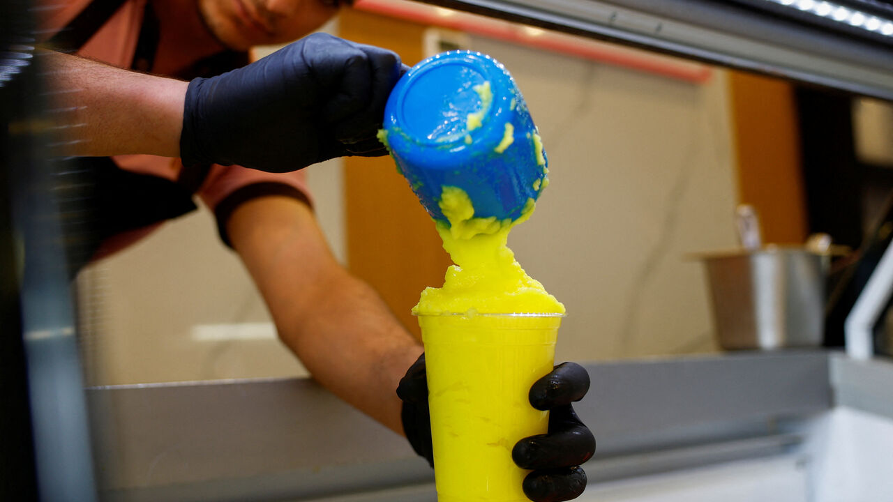 A worker fills a cup of "Barrad", a traditional Palestinian slushy drink with citrus flavours, at a newly opened branch of an ice cream shop that was partially destroyed in Gaza during the ongoing conflict between Israel and Hamas, in Ajman, United Arab Emirates, August 19, 2025. REUTERS/Raghed Wake