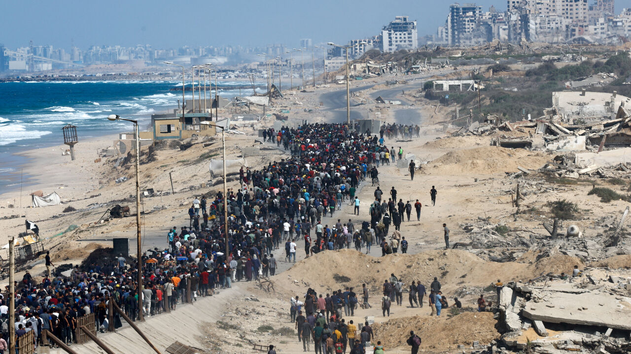 Palestinians, who were displaced to the southern part of Gaza at Israel's order during the war, walk along a road as they attempt to return to the north after a ceasefire between Israel and Hamas in Gaza went into effect, in the central Gaza Strip, October 10, 2025. REUTERS/Mahmoud Issa