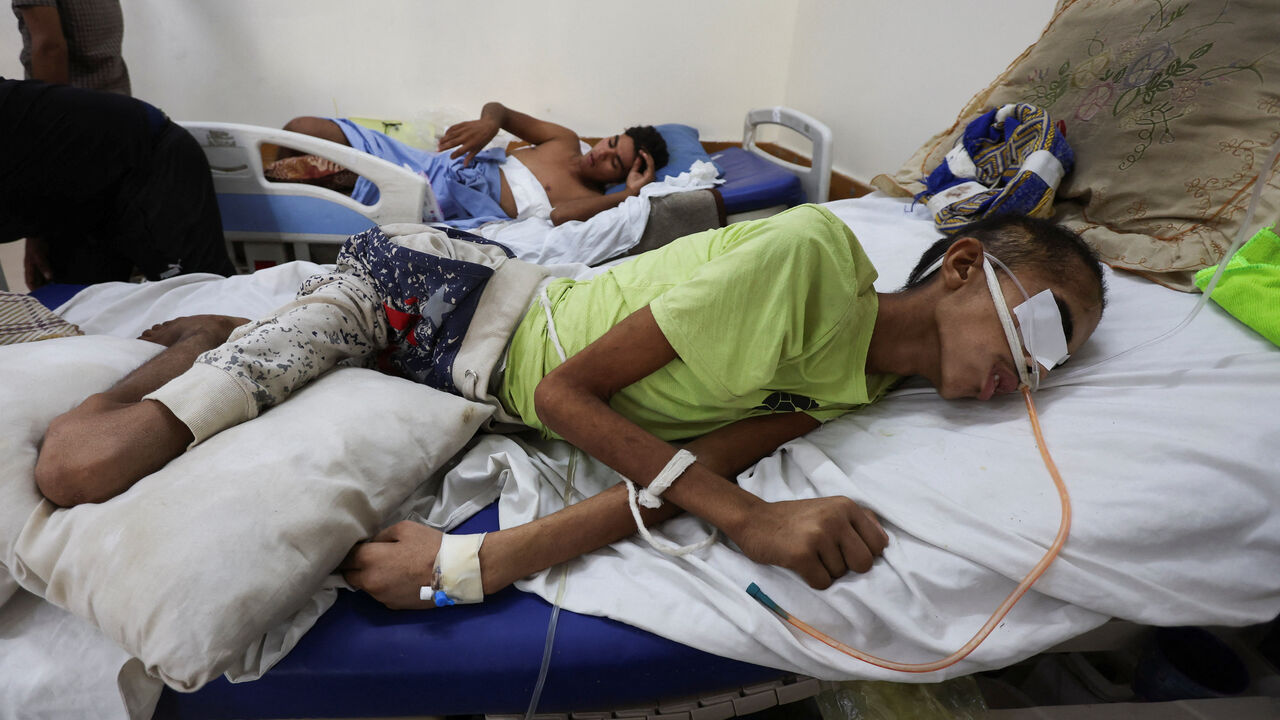 Injured Palestinian Hassan Qlob, 18, who his father says was shot in the head more than two months ago while out seeking food, lies on a bed as he waits for the Rafah crossing to reopen so he can receive treatment abroad, after a ceasefire between Israel and Hamas in Gaza went into effect, at Nasser Hospital in Khan Younis, southern Gaza Strip October 15, 2025. REUTERS/Ramadan Abed