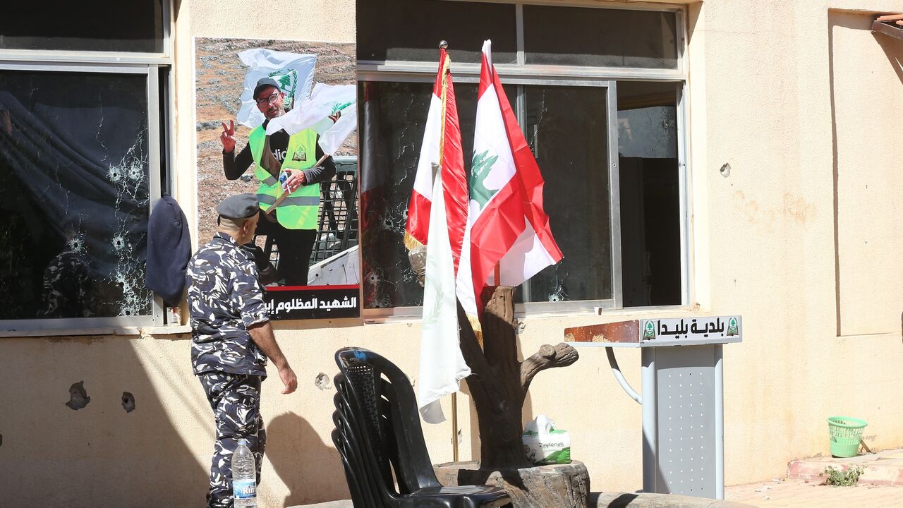 A Lebanese policeman walks past a portrait of Ibrahim Salameh, a Lebanese municipal employee who was killed during an Israeli army raid in the southern border village of Blida, displayed outside the municipality building on Oct. 30, 2025.