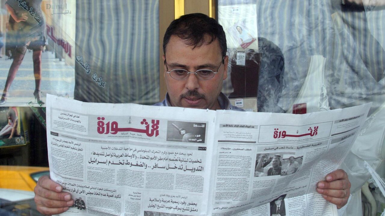 A Syrian reads the state-run daily newspaper al-Thawra outside his shop in downtown Damascus on Sept. 3, 2004.
