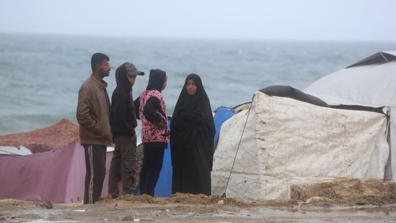 Displaced Palestinians stand next to tents west of Deir al-Balah in central Gaza. The UN resolution calls for the resumption of humanitarian aid deliveries, at scale