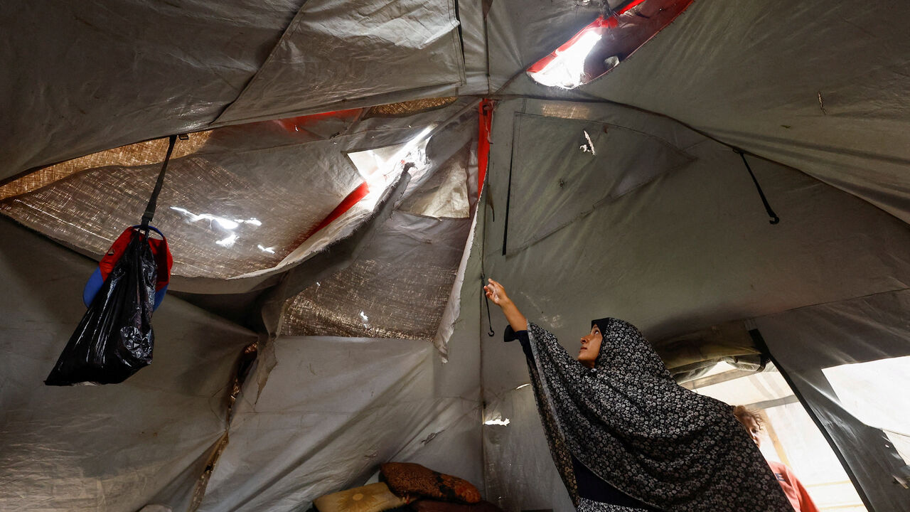 A displaced Palestinian woman shows her torn tent, amid a ceasefire between Israel and Hamas, in Gaza City, November 4, 2025. REUTERS/Mahmoud Issa