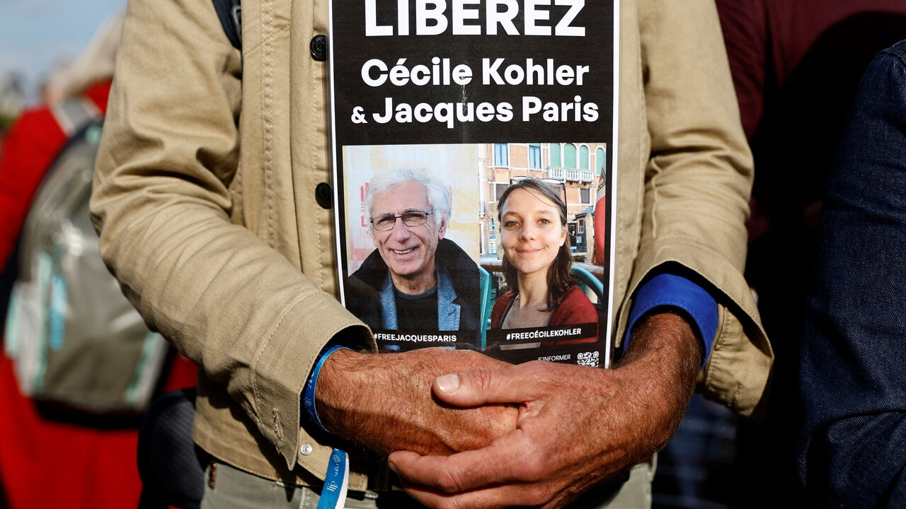 A man holds a placard with the portraits of Cecile Kohler and Jacques Paris, two French citizens held in Iran, during a support rally to mark their three-year detention and to demand their release, at Place de la Nation in Paris, France, May 7, 2025. The slogan reads "Freedom for Cecile Kohler and Jacques Paris". REUTERS/Abdul Saboor