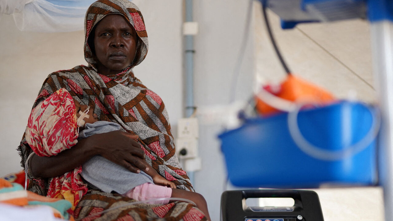 FILE PHOTO: An injured displaced Sudanese woman who fled violence in al-Fashir receives treatment while carrying her child at a makeshift clinic run by Medecins Sans Frontieres (MSF), amid ongoing clashes between the paramilitary Rapid Support Forces (RSF) and the Sudanese army, in Tawila, North Darfur, Sudan November 3, 2025. REUTERS/Mohamed Jamal/File Photo