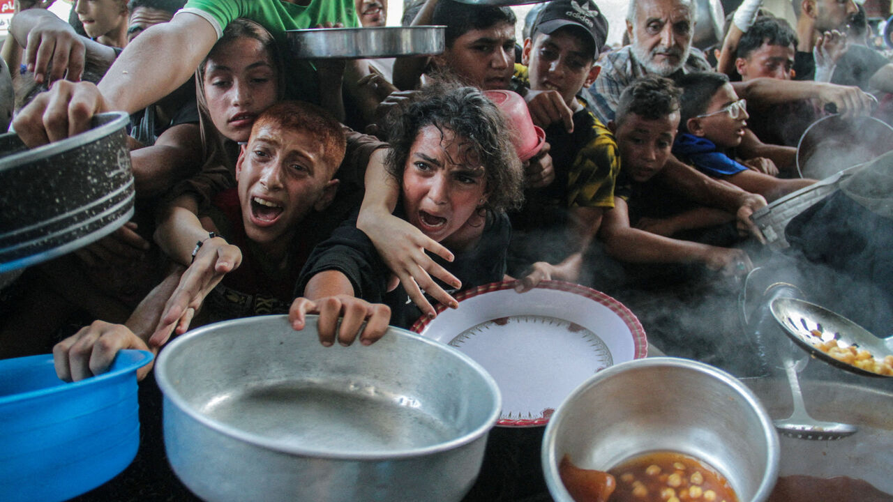 Palestinians gather to receive food cooked by a charity kitchen, amid the Israel-Hamas conflict, in the northern Gaza Strip, September 11, 2024. REUTERS/Mahmoud Issa