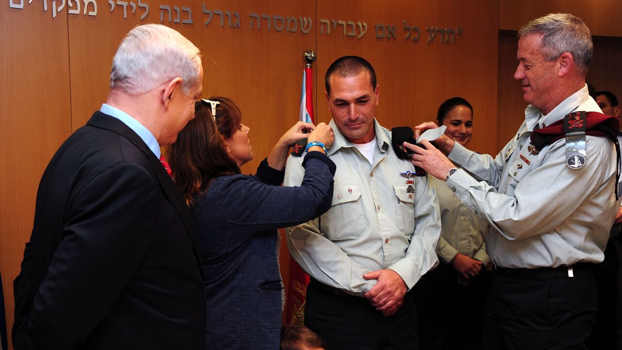 In this handout by the Israeli Government Press Office, Prime Minister Benjamin Netanyahu (L) looks on as military chief of staff Lt.-Gen. Benny Gantz (R) adjusts the epaulettes of Brig. Gen. Eyal Zamir for his swearing in as military secretary, Tel Aviv, Nov. 26, 2012.