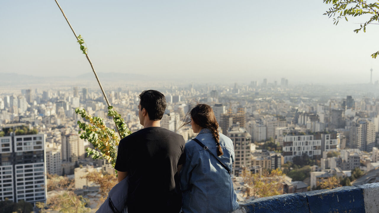 A couple sits facing the skyline of Tehran from Bam-e Tehran in Tehran, Iran on October 24, 2025. (Photo by Bahram / Middle East Images via AFP) (Photo by BAHRAM/Middle East Images/AFP via Getty Images)