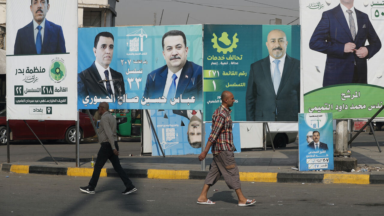 People walk past electoral campaign posters ahead of Iraq's parliamentary elections in central Baghdad on Nov. 6, 2025. 