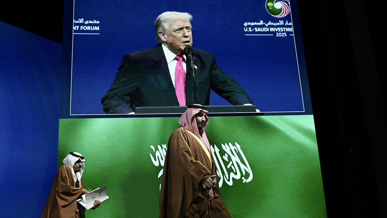 Crown Prince and Prime Minister of the Kingdom of Saudi Arabia Mohammed bin Salman (R) arrives as US President Donald Trump is seen on a screen.