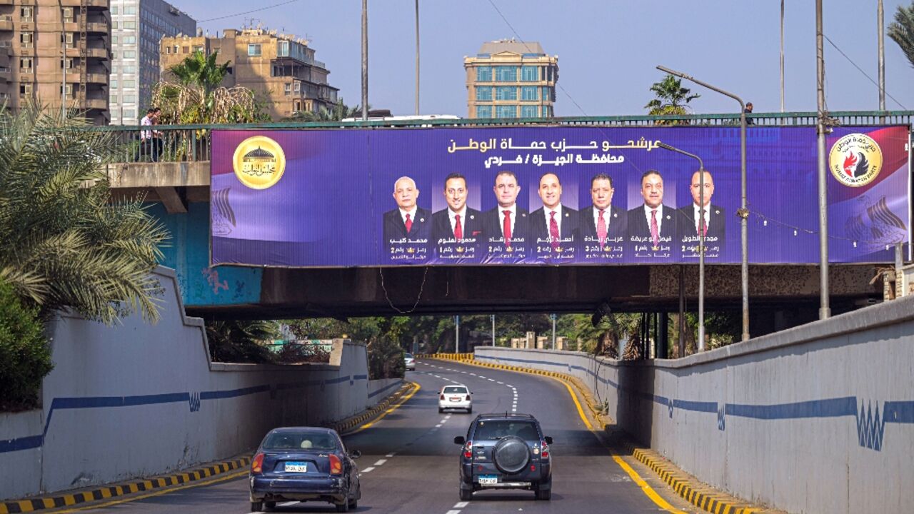 Motorists drive past a campaign billboard in Giza for the Egyptian parliamentary elections