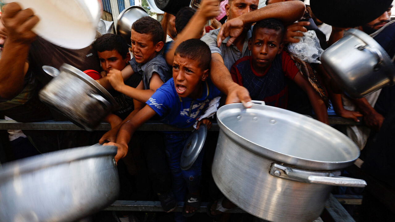 FILE PHOTO: Palestinians gather to receive food from a charity kitchen, in Nuseirat, central Gaza Strip, September 28, 2025. REUTERS/Mahmoud Issa/ File Photo