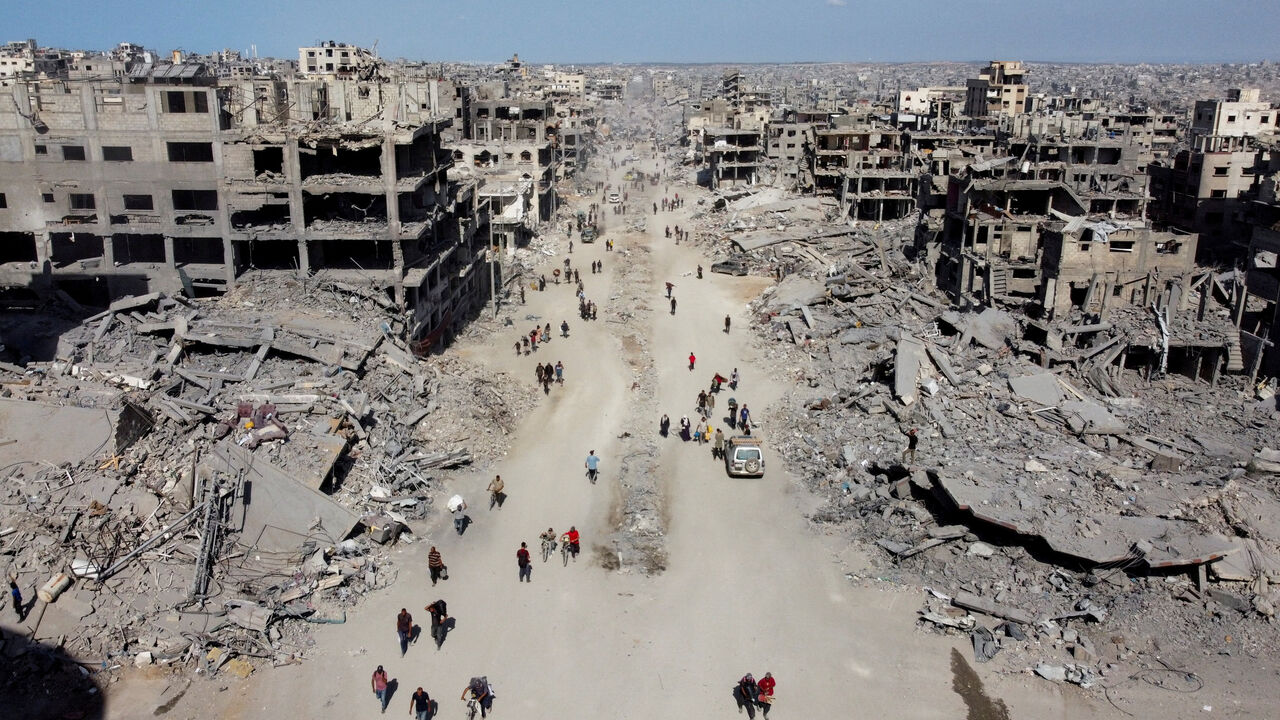 A drone view shows Palestinians walking past the rubble, following Israeli forces' withdrawal from the area, amid a ceasefire between Israel and Hamas in Gaza, in Gaza City, October 11, 2025. REUTERS/Dawoud Abu Alkas/File Photo