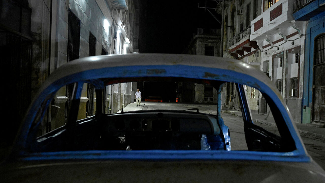 FILE PHOTO: A man walks down a street after power was restored following a partial collapse of the electrical grid that left much of western Cuba in the dark, in Havana, Cuba, December 3, 2025. REUTERS/Norlys Perez/File Photo