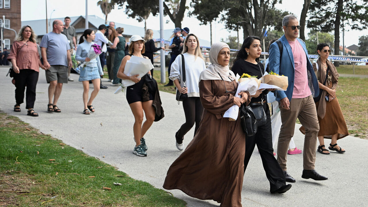 People bring flowers for a makeshift memorial following the attack on a Jewish holiday celebration at Sydney's Bondi Beach, in Sydney, Australia, December 15, 2025. REUTERS/Flavio Brancaleone